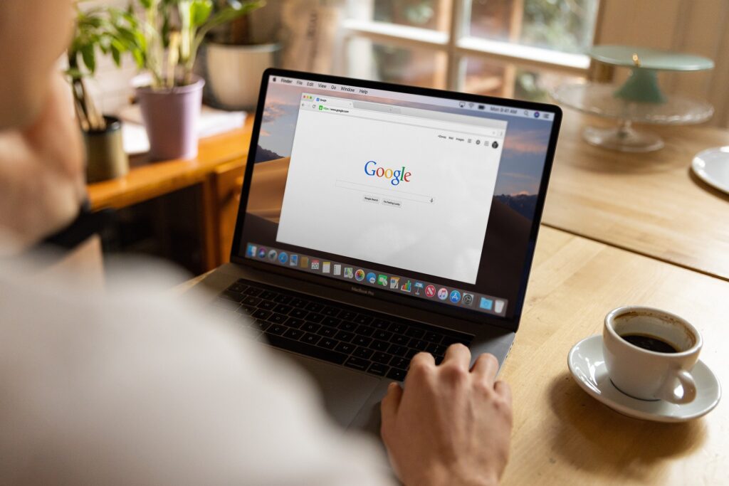 Kannettava tietokone, jossa Googlen hakusivu, ja kahvikuppi